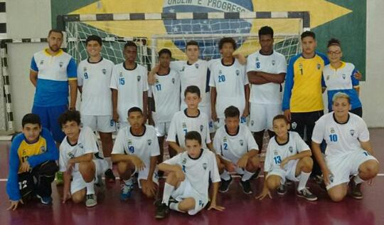 equipe infantil de handebol posando para foto diante do gol