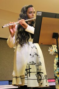 garota toca flauta transversal enquanto observa sua partitura