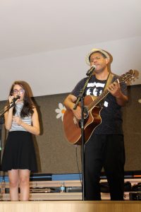 garota canta à direita de um homem cantando e tocando violão