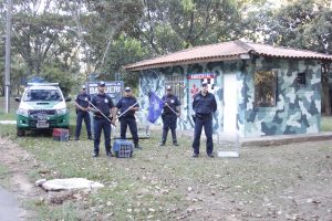 cinco homens da Guarda Ambiental de Barueri posam com armas diante do posto da corporação, com uma viatura atrás e à direita deles