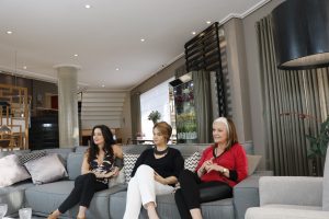 Val Justo, que apresentará novo programa feminino do Alpha Channel, posa com outras duas mulheres sentadas num sofá
