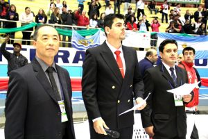 Ruy Koike ao lado de outros dois homens, todos de terno