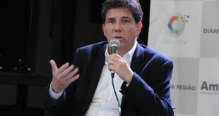 Claudio Piteri sentado e com o microfone na mão participando do debate