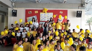 alunos e professores de escola municipal de Barueri segurando balões amarelos em campanha contra a febre amarela