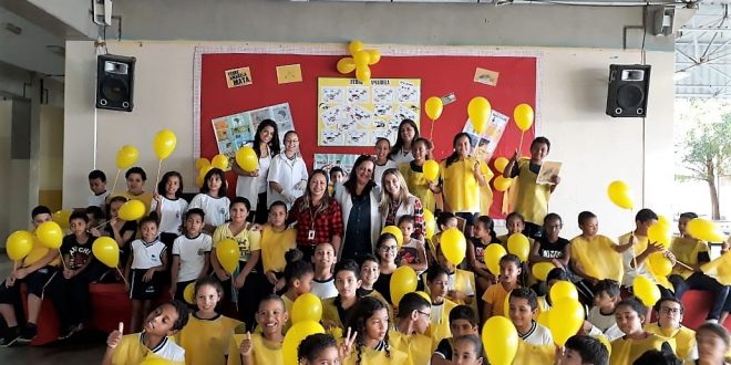 alunos e professores de escola municipal de Barueri segurando balões amarelos em campanha contra a febre amarela