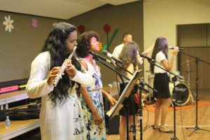 banda se apresentando com flauta transversal, canto e guitarra