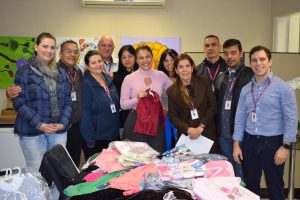 membros do fundo social de solidariedade posam para foto diante de peças doadas durante a campanha do agasalho