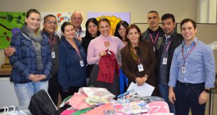 membros do fundo social de solidariedade posam para foto diante de peças doadas durante a campanha do agasalho