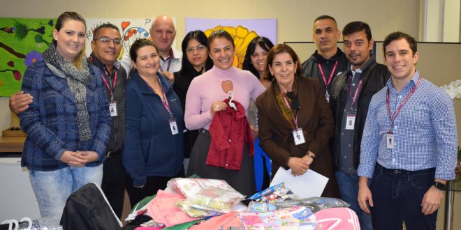 membros do fundo social de solidariedade posam para foto diante de peças doadas durante a campanha do agasalho