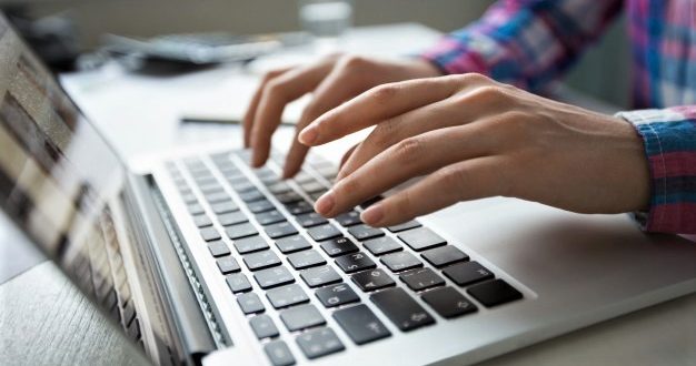 um par de mãos digitando em um notebook