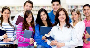 um grupo de estudantes segura apostilas e sorri para a câmera