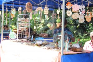 um estande da feira de artes, decoração e artesanato, com diversos objetos  de artesanato pendurados e dispostos