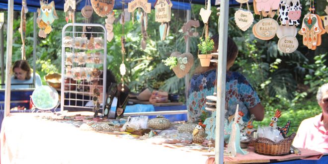 um estande da feira de artes, decoração e artesanato, com diversos objetos de artesanato pendurados e dispostos