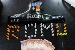 entorpecentes dispostos numa mesa de modo a formar a palavra 'ROMU'; há também cédulas de real