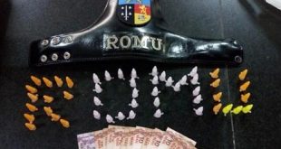 entorpecentes dispostos numa mesa de modo a formar a palavra 'ROMU'; há também cédulas de real