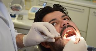 um caminhoneiro tendo sua boca examinada pelas mãos de um(a) dentista(a)