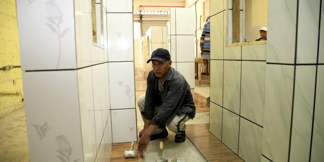 um pedreiro colocando um piso