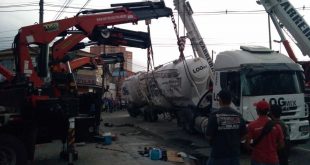 carreta tombada sendo desvirada por dois guindastes