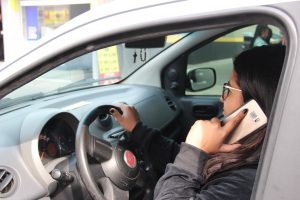 uma motorista fala ao celular enquanto conduz seu carro