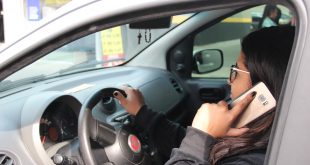 uma motorista fala ao celular enquanto conduz seu carro