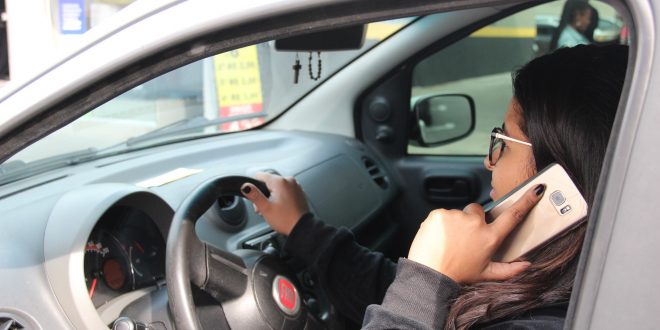 uma motorista fala ao celular enquanto conduz seu carro
