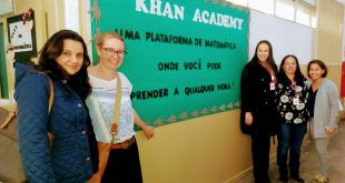 representantes posam ao lado de mural da escola com professoras