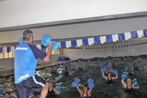 mulheres se exercitando em piscina sob orientação de um profissional