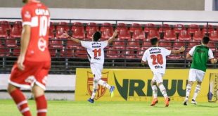 jogadores do Oeste celebram um gol com um jogador do CRB caminhando em primeiro plano