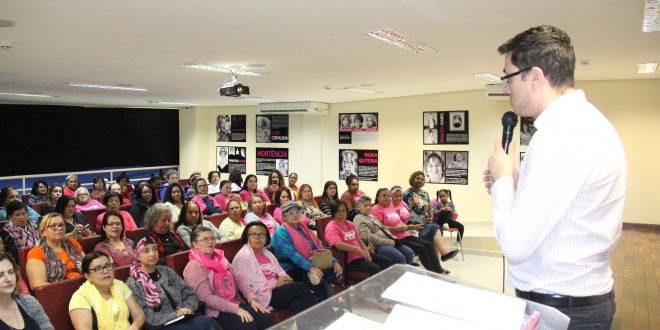 o médico Ricardo Oliveira da Fonseca fala ao microfone para um auditório lotado de mulheres