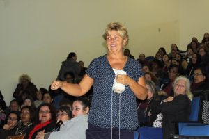 Leigh Ann Kramer proferindo sua palestra com várias educadoras lotando auditório ao fundo