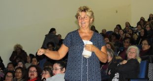 Leigh Ann Kramer proferindo sua palestra com várias educadoras lotando auditório ao fundo