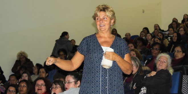 Leigh Ann Kramer proferindo sua palestra com várias educadoras lotando auditório ao fundo
