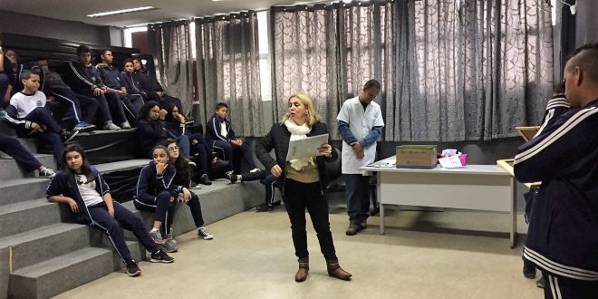 alunos sentados na plateia enquanto professora organiza o quiz