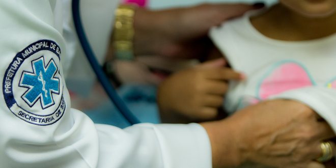 uma criança cujo rosto não é mostrado sendo examinada por um(a) médico(a) em barueri