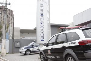 fachada da delegacia de defesa da mulher de barueri, com uma viatura da polícia civil e outra da guarda civil estacionadas em frente