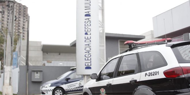 fachada da delegacia de defesa da mulher de barueri, com uma viatura da polícia civil e outra da guarda civil estacionadas em frente