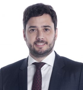 Francisco Finocchiaro de terno sorrindo para a câmera ante um fundo branco