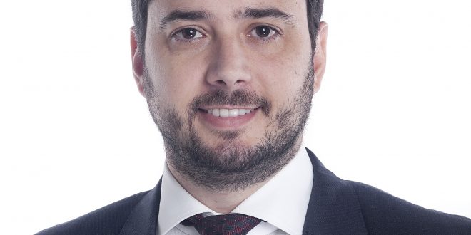 Francisco Finocchiaro de terno sorrindo para a câmera ante um fundo branco